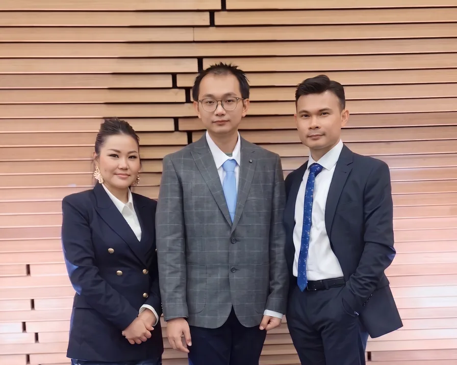 The Jellybytes team — three colleagues in business dress standing in front of a horizontal timber-slat wall